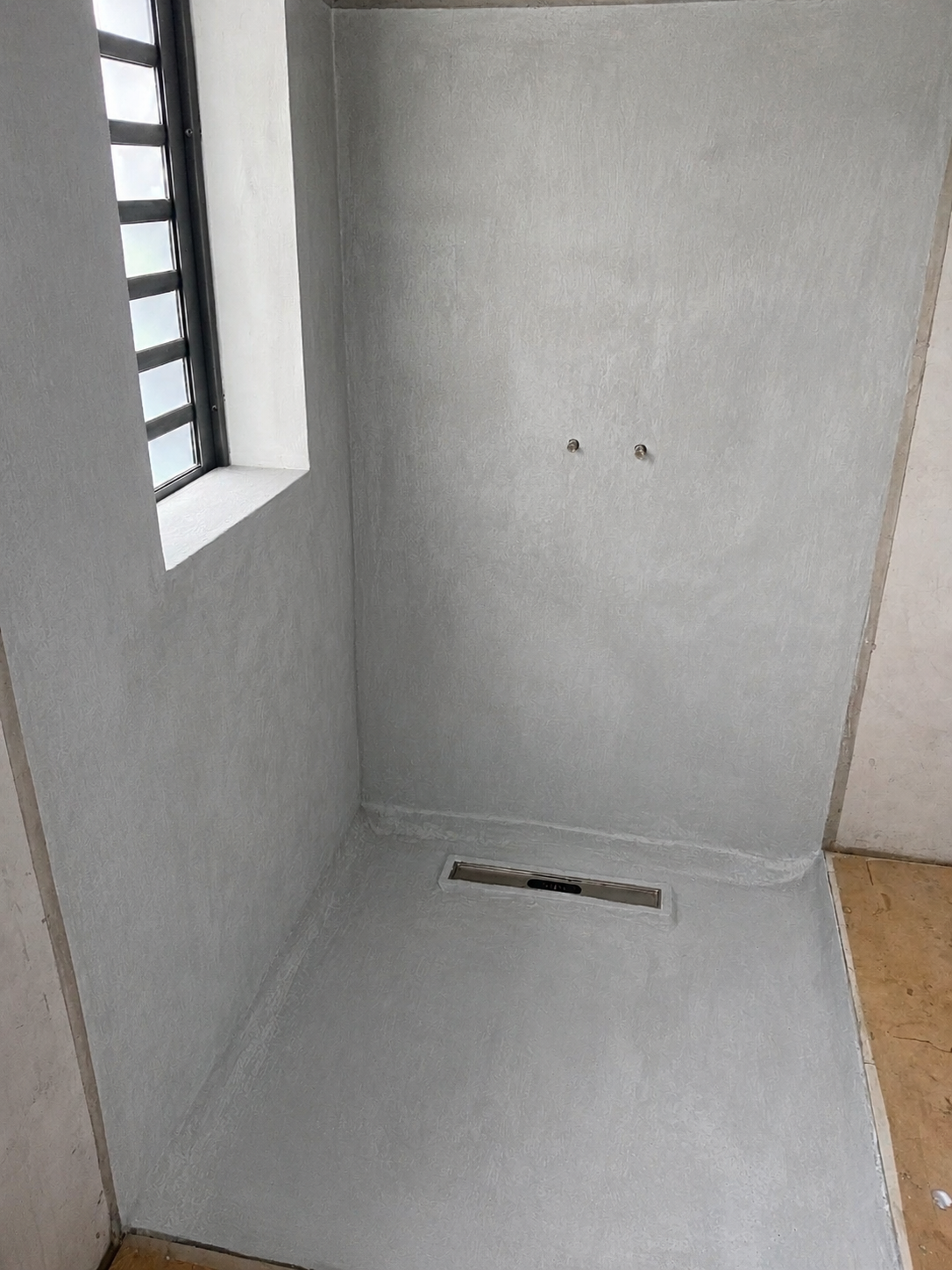 Étanchéité cimentaire appliquée sur les murs et le sol d'une douche avant carrelage à Maurice.
